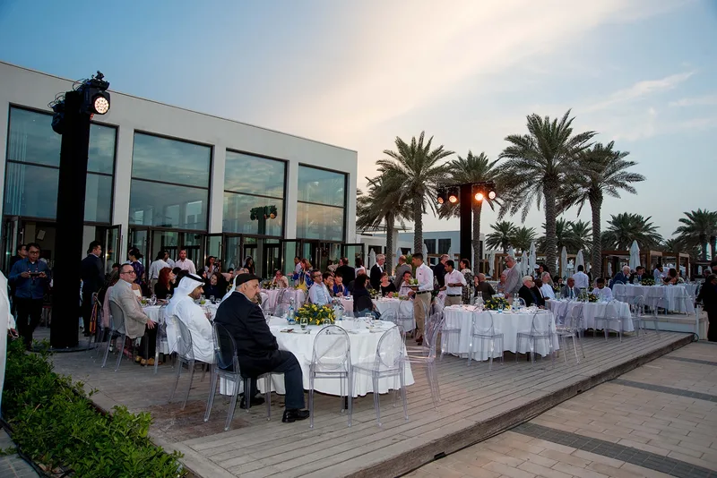 Evolution Furniture outdoor dining setup with round tables, transparent chairs and event lighting
