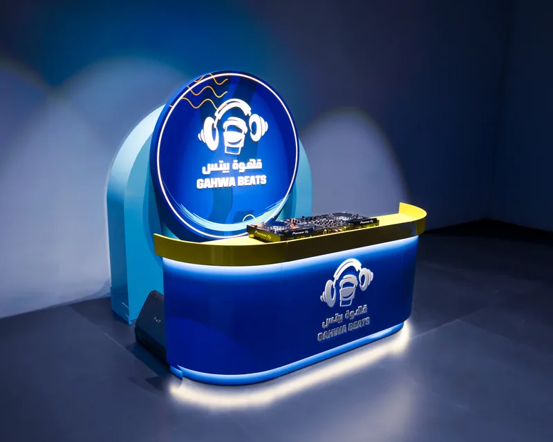 Custom-built illuminated blue DJ console setup featuring circular branded backdrop panel