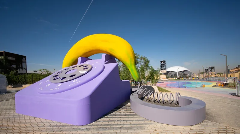 Giant oversized purple rotary phone sculpture with banana handset installed as public art at Diriyah Oasis