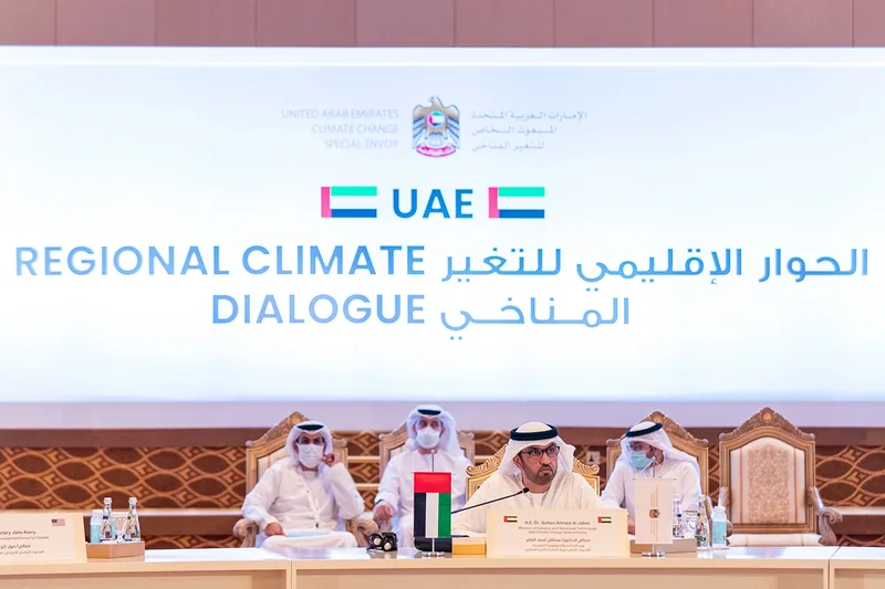UAE Regional Climate Dialogue plenary setup with branded backdrop, delegate table and national flags