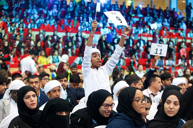 Youth Tolerance Rally audience with students holding transport signs inside a large indoor arena